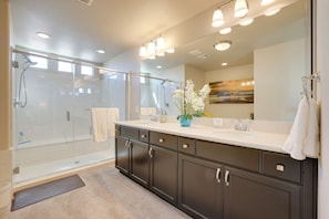 A modern bathroom with a glass-enclosed shower, a large mirror, and a vanity with dark cabinets. - Multi-level Group Haven! 9 Mi to Allegiant Stadium (Las Vegas)