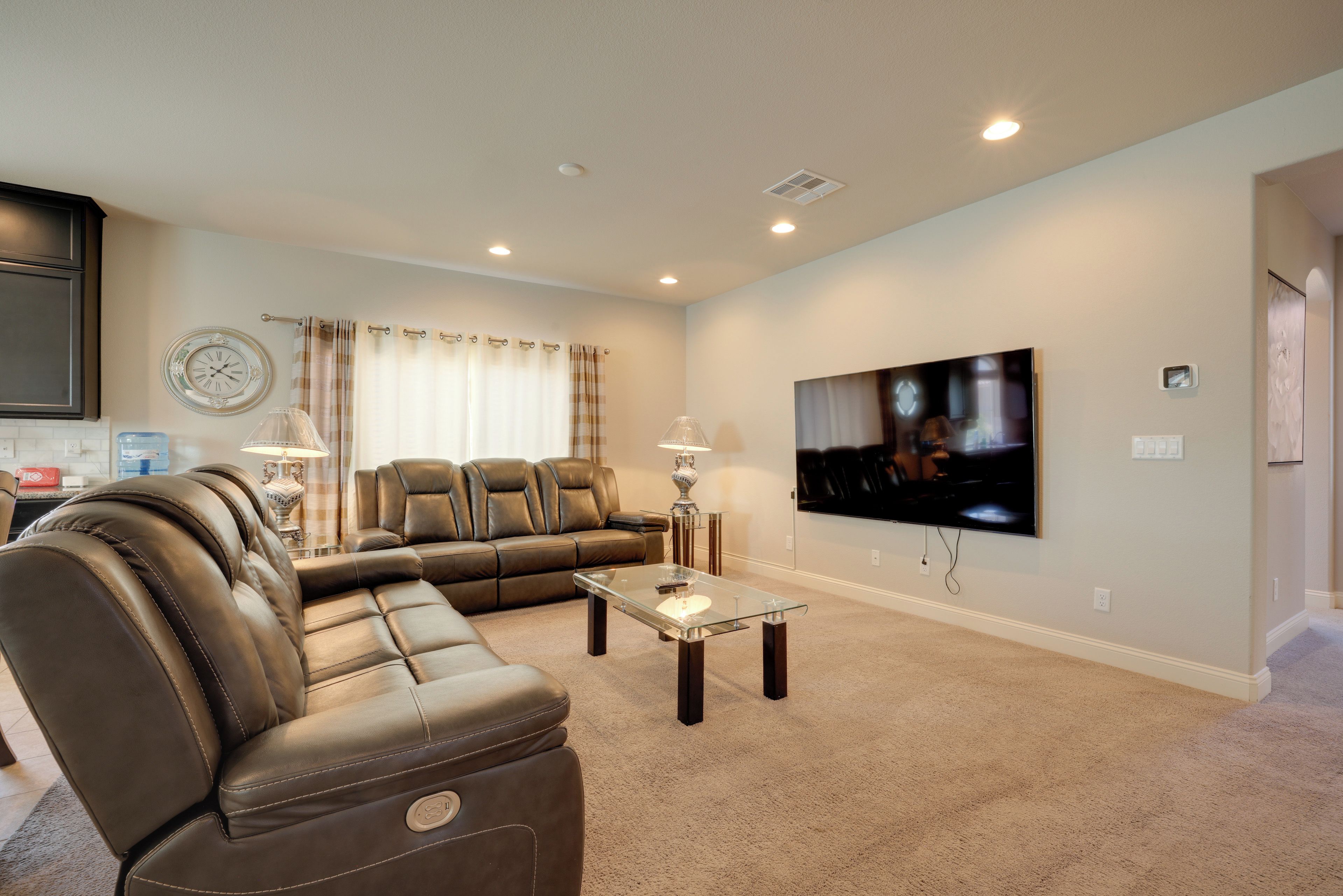 A living room with a sectional sofa, a flat-screen TV, and a glass coffee table.
