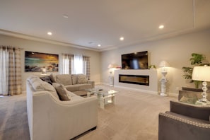 A living room with a sofa, a coffee table, a fireplace, and a television mounted on the wall. - Multi-level Group Haven! 9 Mi to Allegiant Stadium (Las Vegas)