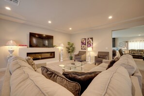A living room with a flat-screen TV, two armchairs, a sofa, a coffee table, and a fireplace.