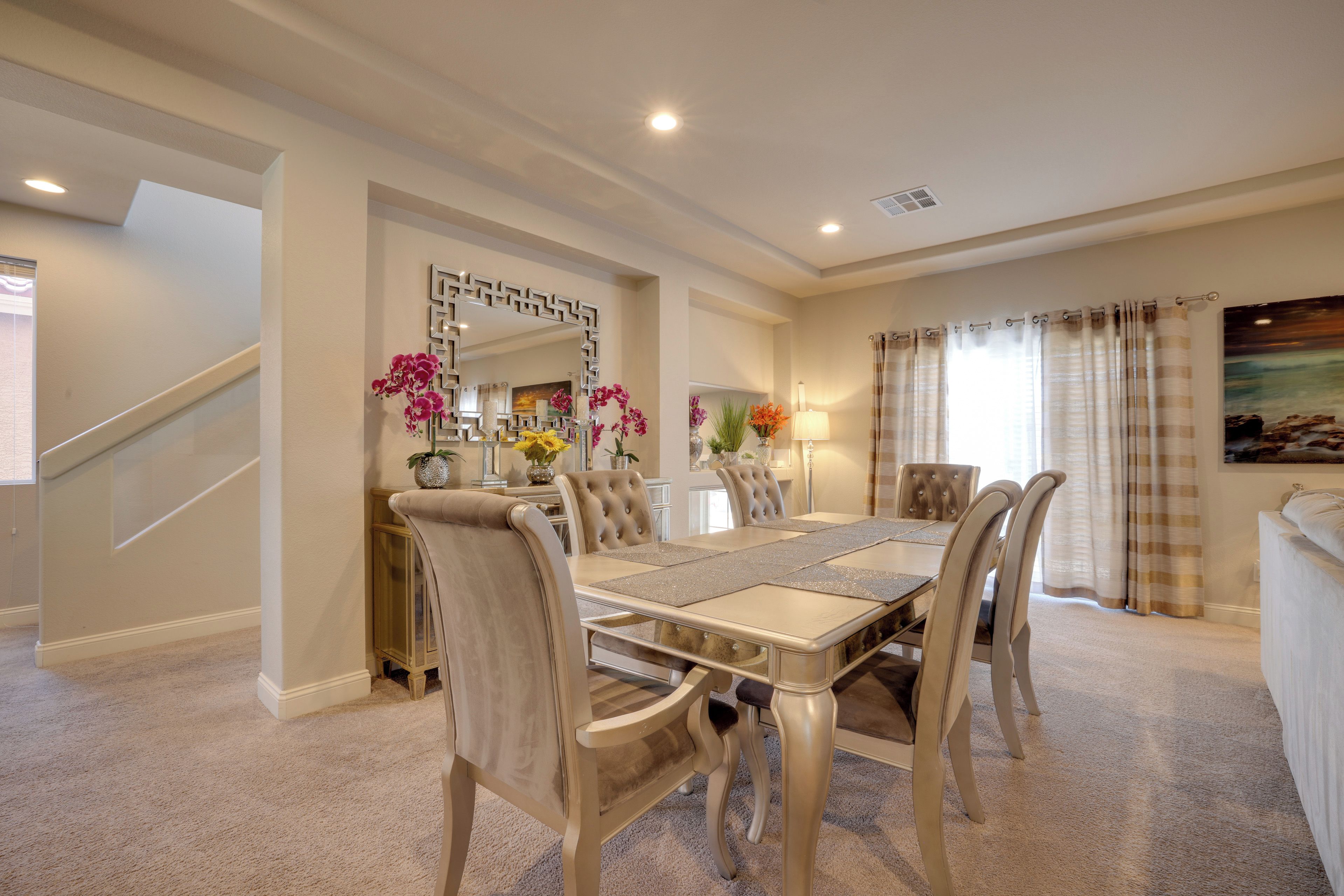 Comedor con una mesa rectangular, seis sillas y un espejo decorativo.