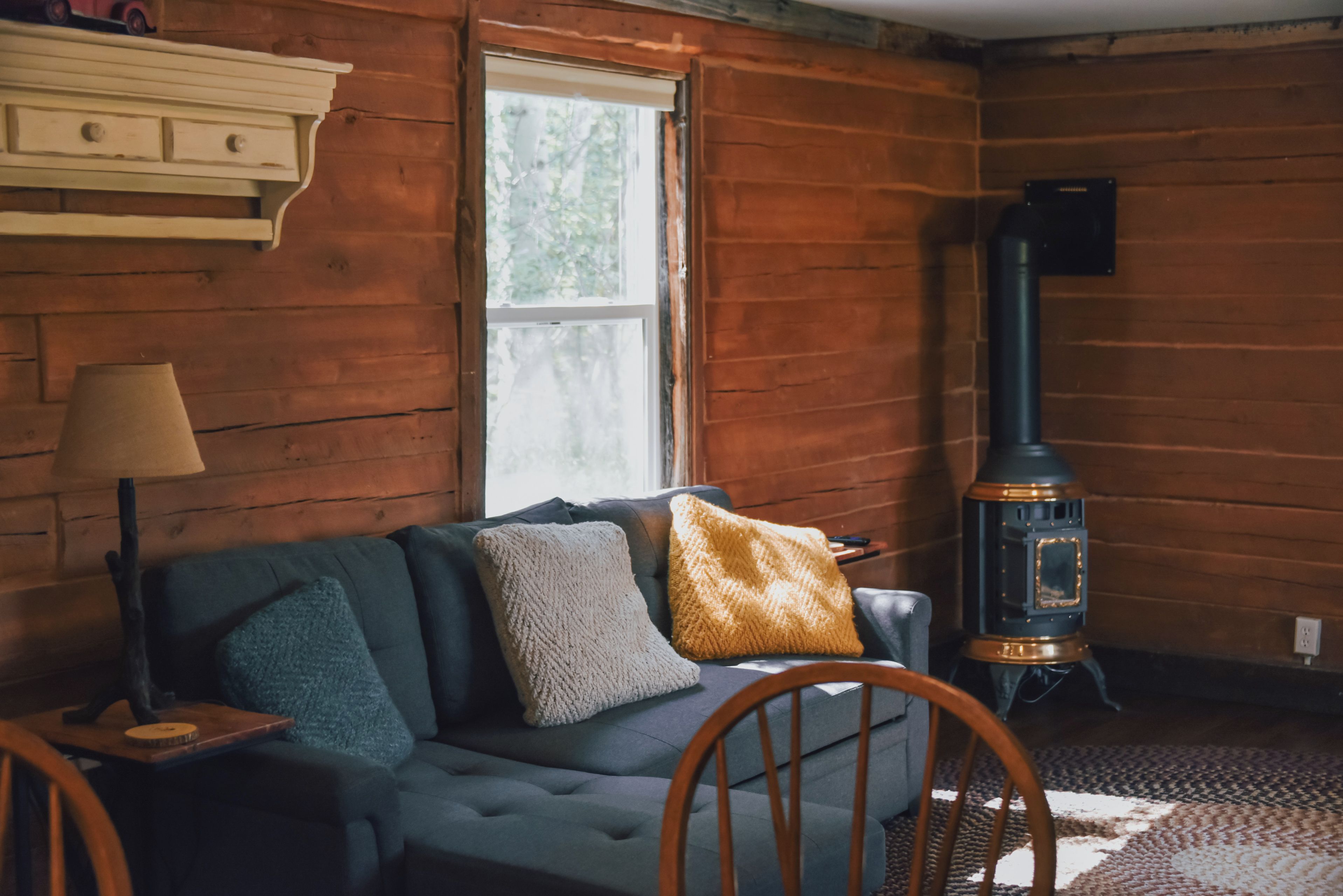 A cozy living room with a sofa, a lamp, and a wood-burning stove.