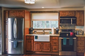 A kitchen with wooden cabinets, a stainless steel refrigerator, a microwave, and a stove.