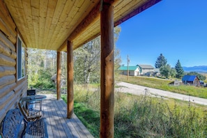 A wooden cabin with a porch, a table, and chairs.