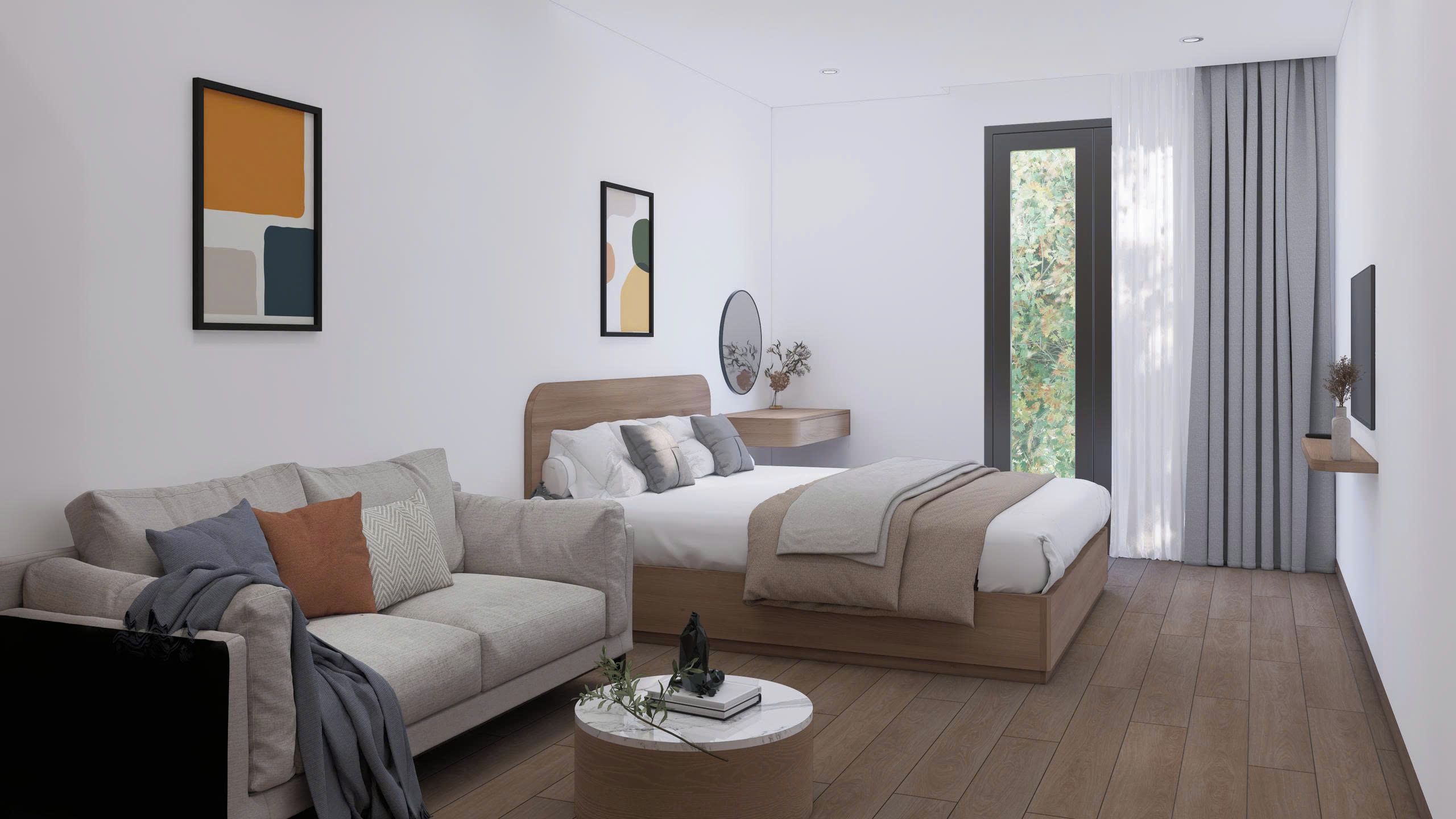 Habitació d'hotel moderna amb un sofà, un llit, una taula de nit amb un mirall i obres d'art a les parets.