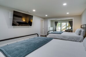 A hotel room with two beds, a flat-screen TV mounted on the wall, and a window with curtains.