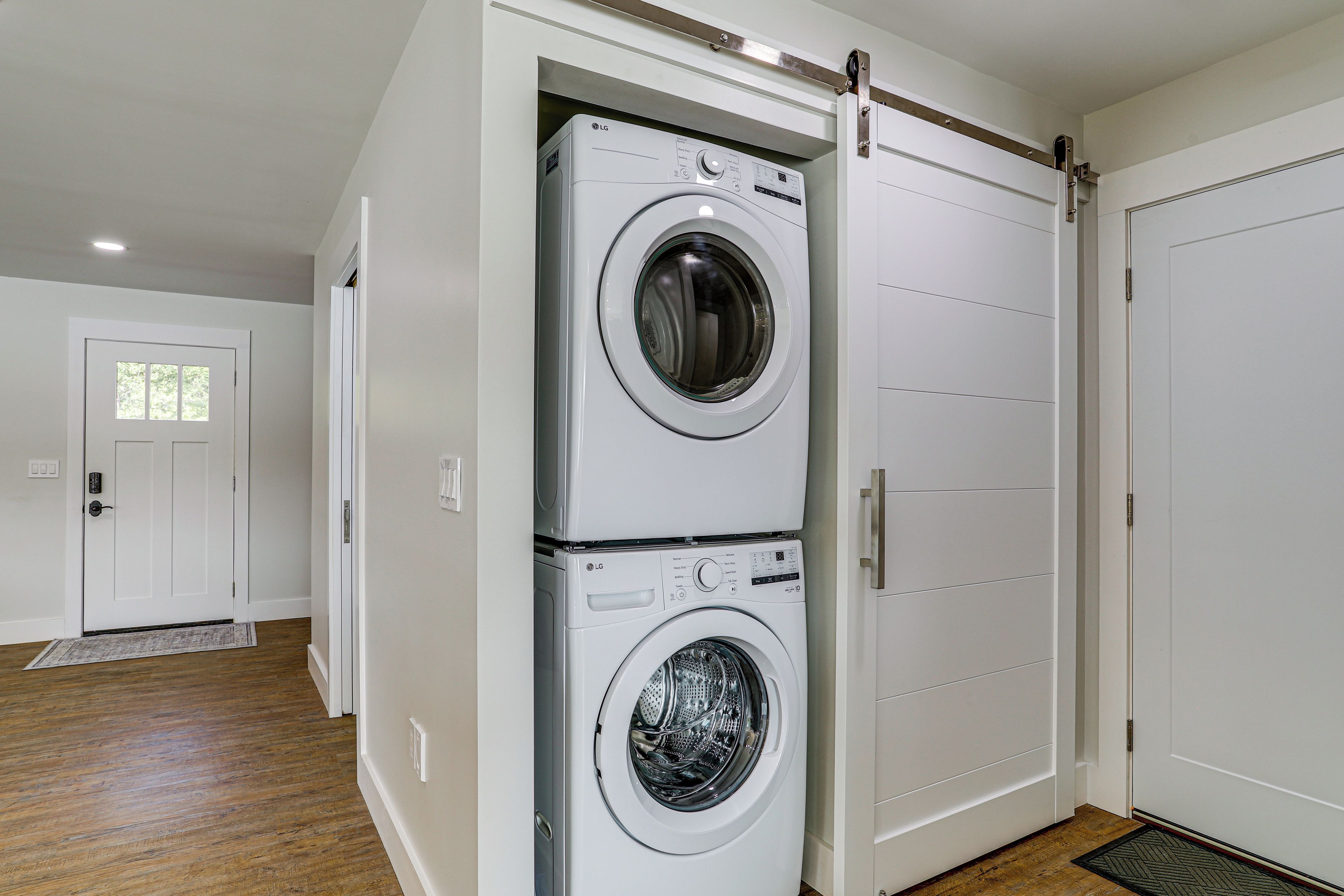 A laundry room with two stacked front-loading washing machines and a sliding door closet.