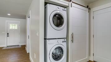 A laundry room with two stacked front-loading washing machines and a sliding door closet.