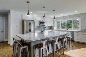 A modern kitchen with white cabinets, stainless steel appliances, and a large island with bar stools.