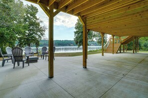 Un porche techado al aire libre con suelo de hormigón, vigas de madera y sillas Adirondack.