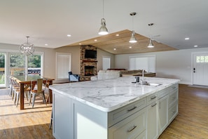 A spacious kitchen with a large island, wooden ceiling, and modern lighting fixtures.