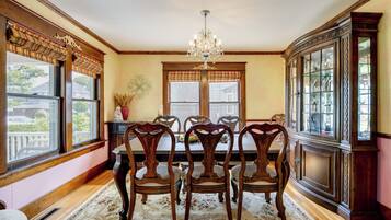 A dining room with a chandelier, wooden chairs, a floral rug, and a china cabinet.