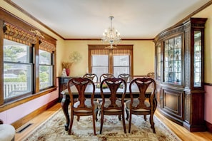 A dining room with a chandelier, wooden chairs, a floral rug, and a china cabinet. - Near Lake Erie Beaches! Angola Gem w/ Patios (Angola)