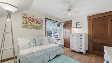 A bedroom with a bed, a dresser, a ceiling fan, and a window with blinds.