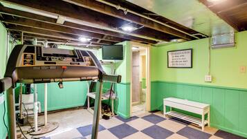 A room with a control panel, a bench, a wall-mounted television, and a motivational quote.