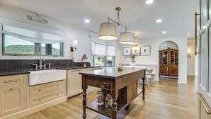 A spacious kitchen with a large island, wooden cabinetry, and a view of the outdoors. - Mtn Views, On the White River: Norfork Getaway (Norfork)