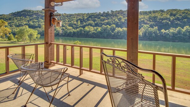 A covered outdoor area with a view of a lake and forest. There are metal chairs and a table. - Mtn Views, On the White River: Norfork Getaway (Norfork)