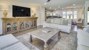 A spacious living room with a large flat-screen TV, a wooden cabinet, a white sofa, and a coffee table. - Mtn Views, On the White River: Norfork Getaway (Norfork)