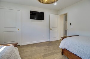 Un dormitorio con una cama, un televisor montado en la pared y dos puertas.