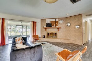 A modern living room with a fireplace, a sofa, a chair, and a view through large windows. - Families w/ Pets Welcome! Retreat 14 Mi to Tampa (Brandon)