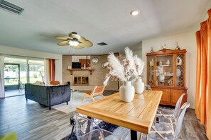 A spacious living room with a wooden dining table, clear glass chairs, a black sofa, and a large wooden cabinet with glass doors. - Families w/ Pets Welcome! Retreat 14 Mi to Tampa (Brandon)