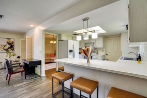 A modern kitchen with a central island, bar stools, and a dining area with a sofa and chairs. - Families w/ Pets Welcome! Retreat 14 Mi to Tampa (Brandon)
