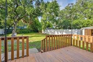 A wooden deck with a railing, surrounded by a grassy yard and trees. - South Tampa Stay w/ Backyard & Fire Pit! (Tampa)