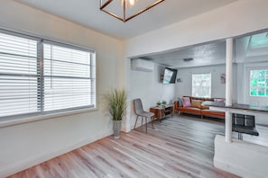 Un salón espacioso con piso de madera, un sofá, una mesa de comedor y una planta en maceta.