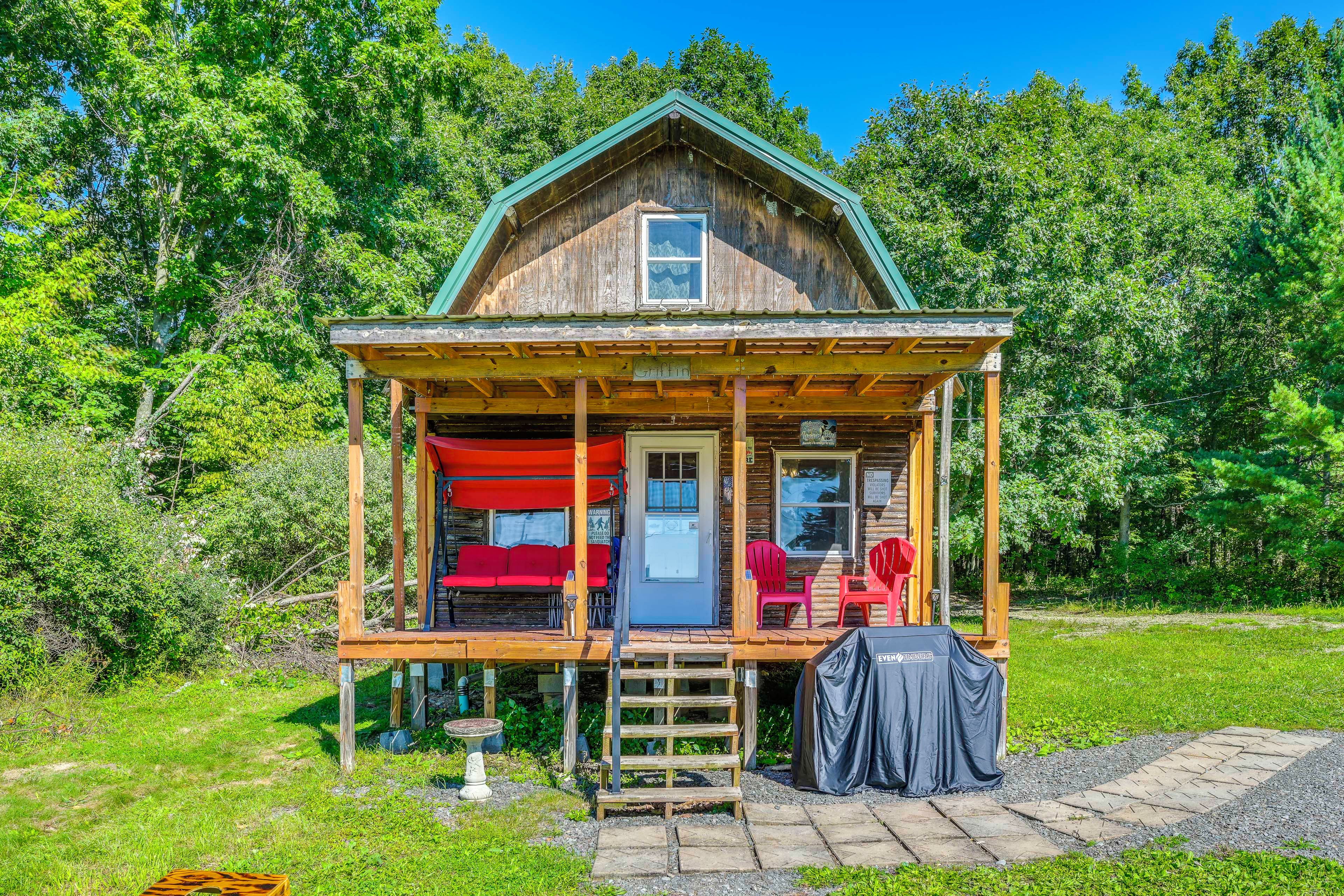 A wooden cabin with a porch, a covered outdoor seating area, and a small garden.