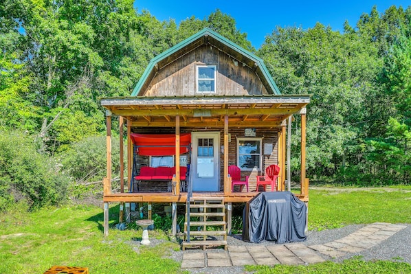 A wooden cabin with a porch, a covered outdoor seating area, and a small garden.