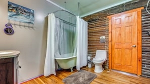 A bathroom with a wooden floor, a bathtub, a toilet, and a wooden door. - 100-acre Milan Cabin w/ Fire Pit & Shared Pond! (Milan)