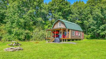 A rustic cabin with a porch, surrounded by lush greenery.