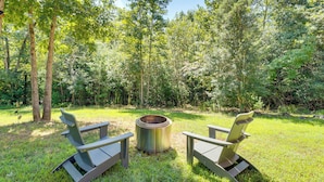 A fire pit with two Adirondack chairs in a grassy area surrounded by trees. - 4 Mi to Cherokee Lake! Wooded Escape Near Hiking (Murphy)