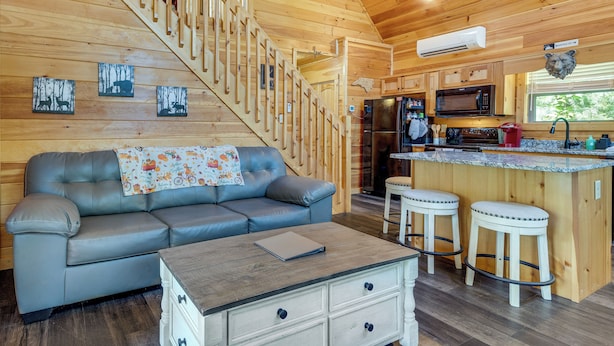 A wooden interior with a sofa, a dining area, and a kitchen. - 4 Mi to Cherokee Lake! Wooded Escape Near Hiking (Murphy)