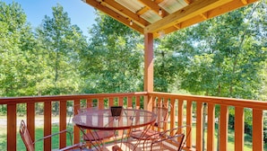 A wooden deck with a round metal table and chairs, surrounded by a wooden railing, overlooking a forested area. - 4 Mi to Cherokee Lake! Wooded Escape Near Hiking (Murphy)
