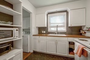 A modern kitchen with white cabinetry, a built-in oven, a microwave, and a window with blinds. - East Memphis Duplex Near Midtown & Downtown (Memphis)