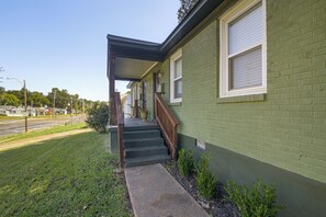 A two-story building with a green exterior, a covered porch, and a staircase leading to the entrance. - East Memphis Duplex Near Midtown & Downtown (Memphis)
