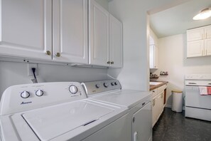 A laundry area with a front-loading washer and dryer, white cabinets, and a stove. - East Memphis Duplex Near Midtown & Downtown (Memphis)