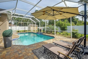 Una piscina exterior techada con zona de patio, que incluye sillones y una mesa.