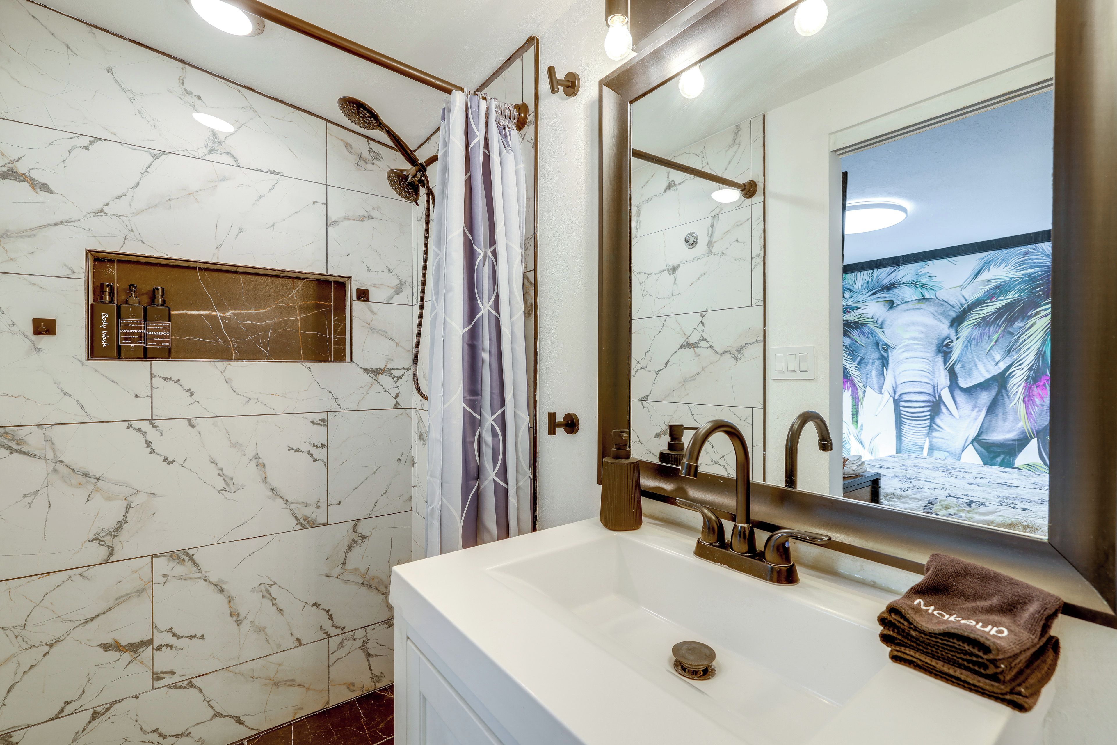 Un baño con lavamanos blanco, un espejo y una ducha con cortina.