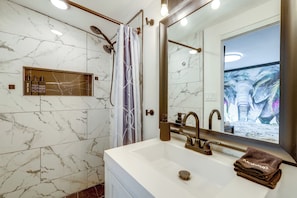 A bathroom with a white sink, a mirror, and a shower with a curtain. - Phoenix Studio Near Downtown w/ Step-free Entry (Phoenix)