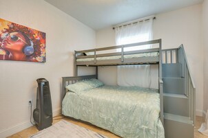 A bunk bed with a staircase, a radiator, and a painting on the wall.