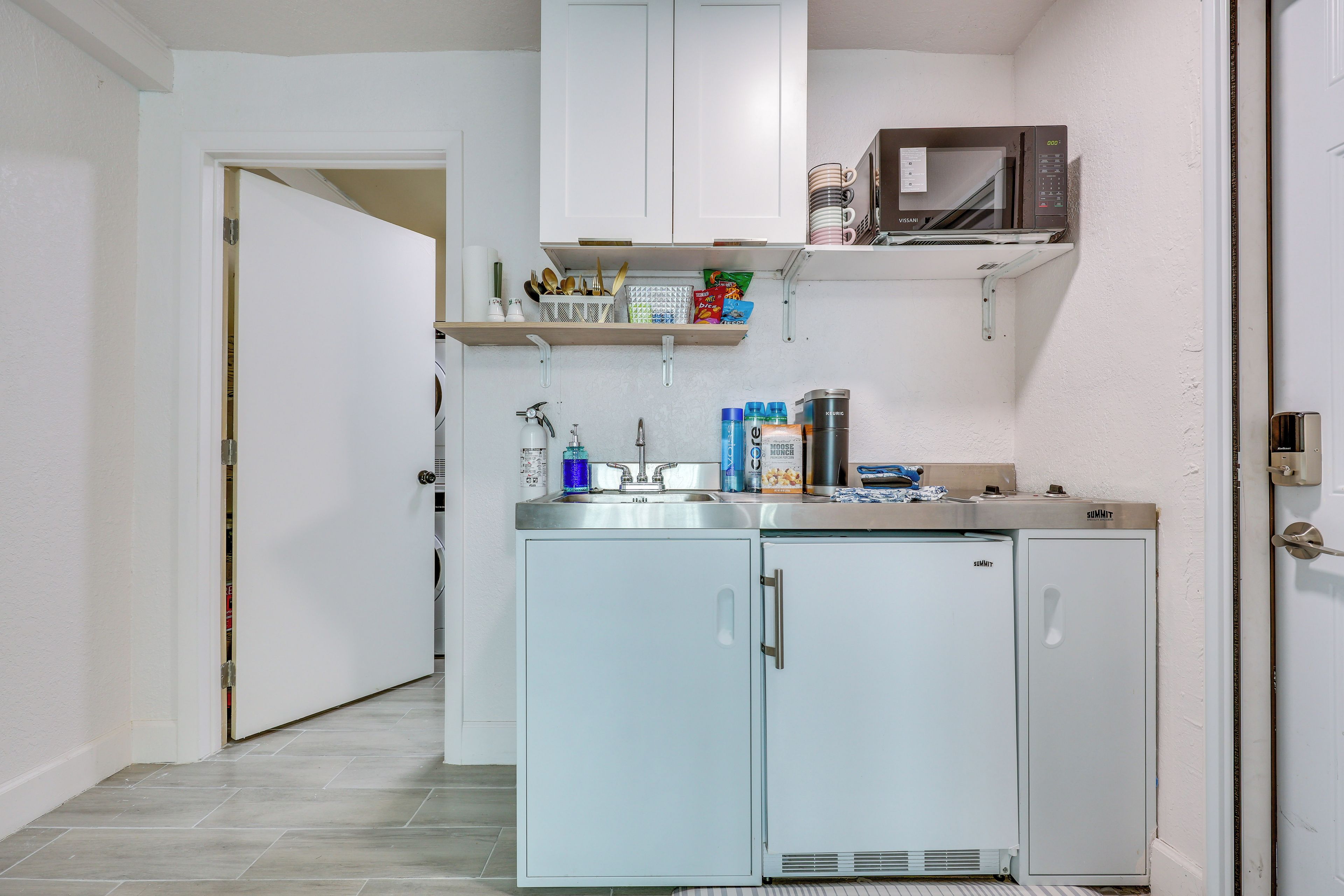 A compact kitchenette with a microwave, a sink, and a refrigerator.