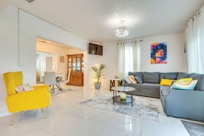 Una sala de estar moderna con un sofá, un sillón amarillo, una mesa de centro y una planta en maceta.