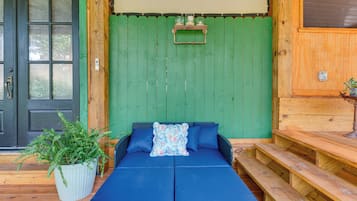 Una habitación con pared verde, puerta negra, sofá con cojines azules y una mesita con una planta.