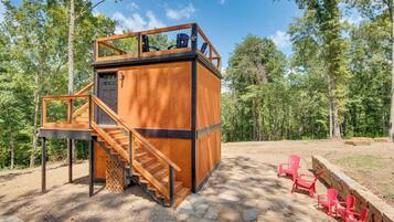 A wooden cabin with a balcony and a staircase leading to a second level.