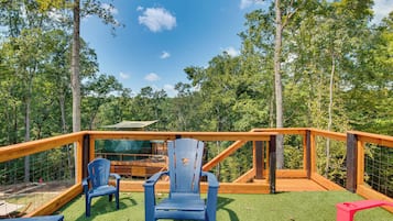 Una terraza de madera con cerramiento de vidrio, rodeada por un bosque.