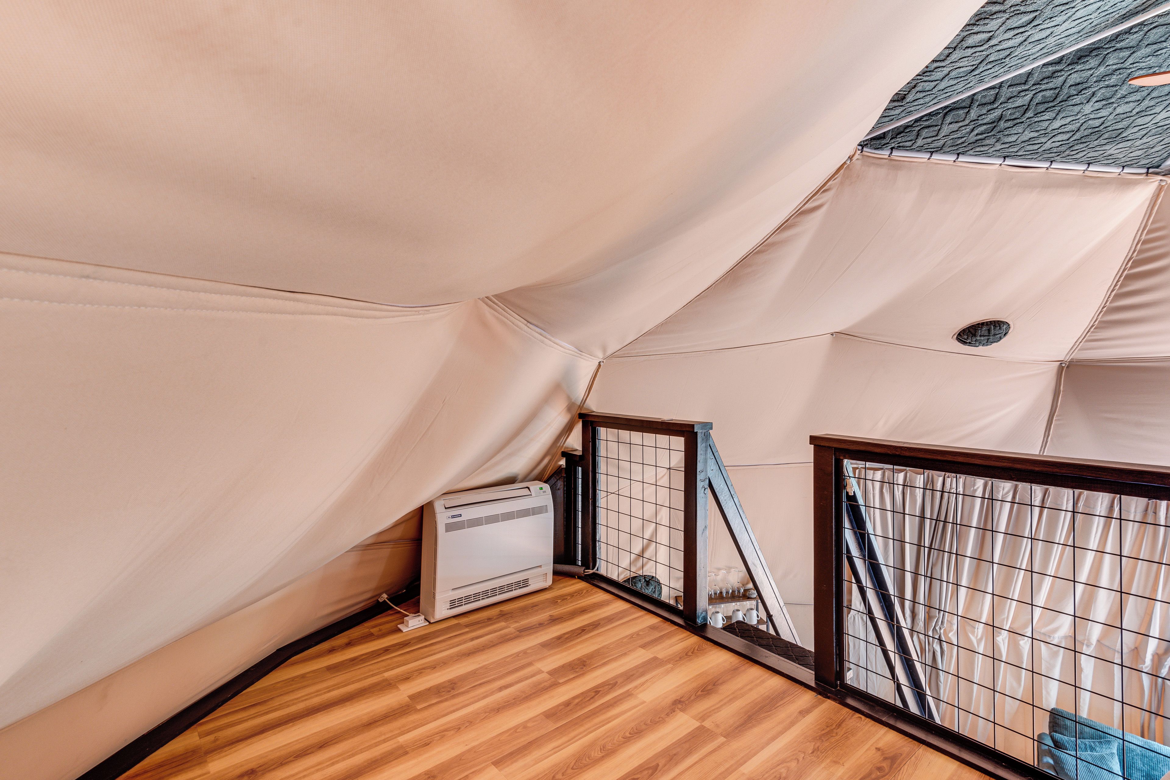 A tent-like structure with a wooden floor and a white air conditioning unit.