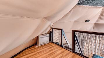 A tent-like structure with a wooden floor and a white air conditioning unit.