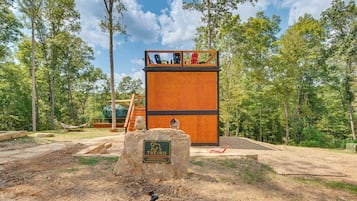 A wooden cabin with a deck, surrounded by trees.